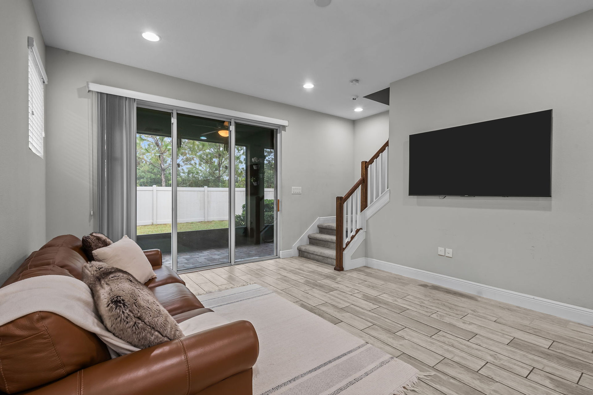 brown couch in living area with tv mounted on wall
