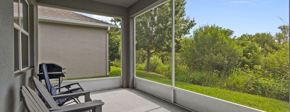 backyard screened enclosure patio with lawn chairs and grill