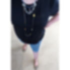 Colorful beaded bracelets on a wrist, featuring green, black, white, and gold beads. Background shows textured green fabric. Bright mood.