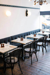 Interior at Angelas, Margate. There is a sofa booth along the wall, a table and a chair.