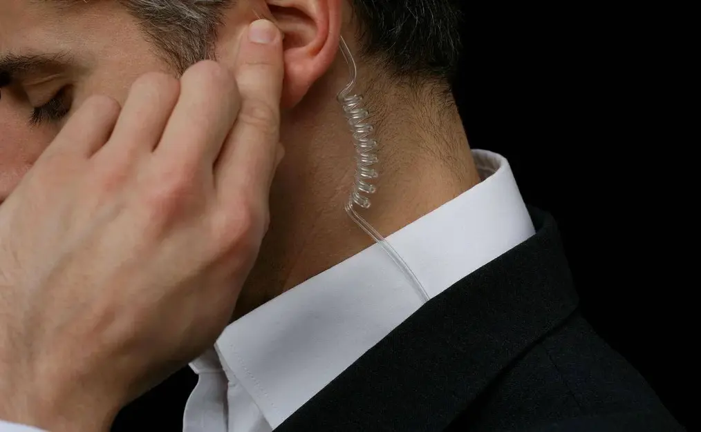 A man in a suit with a wired ear piece.
