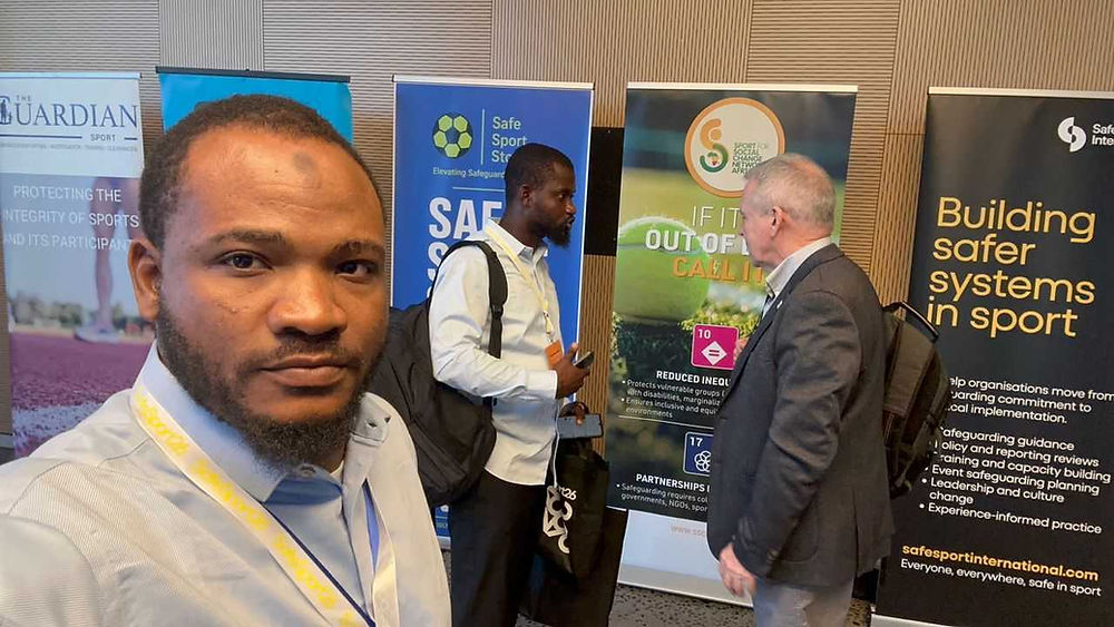 Men at conference with 'Building safer systems in sport' banner.
