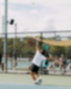 Man serving tennis ball on outdoor court