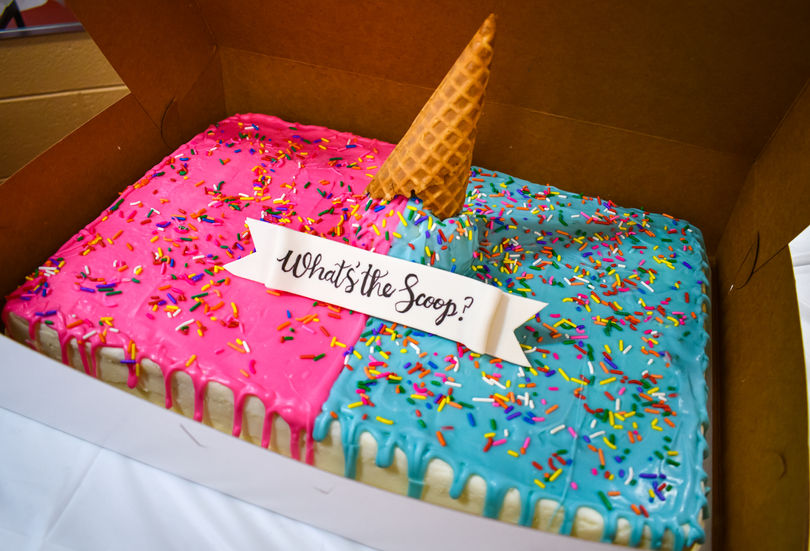 Custom decorated gender reveal celebration cake on display table before cutting