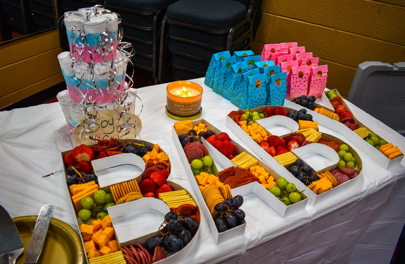 Festive party food display featuring fresh fruit trays arranged to spell out the word BABY