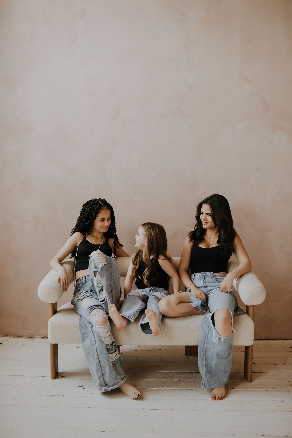 three siblings sitting on a white couch laughing at The Sela Loft in Concord NC