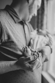 a close up of baby feet while her dad is holding her for newborn portraits in lake norman