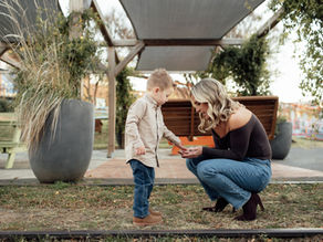 a mom kneeling down to see a rock that her young son placed in her hand at Camp North End in Charlotte NC