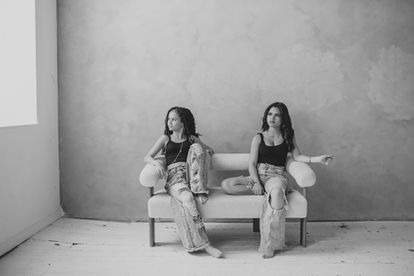 two teenage girls sitting on a white couch with matching outfits in black and white