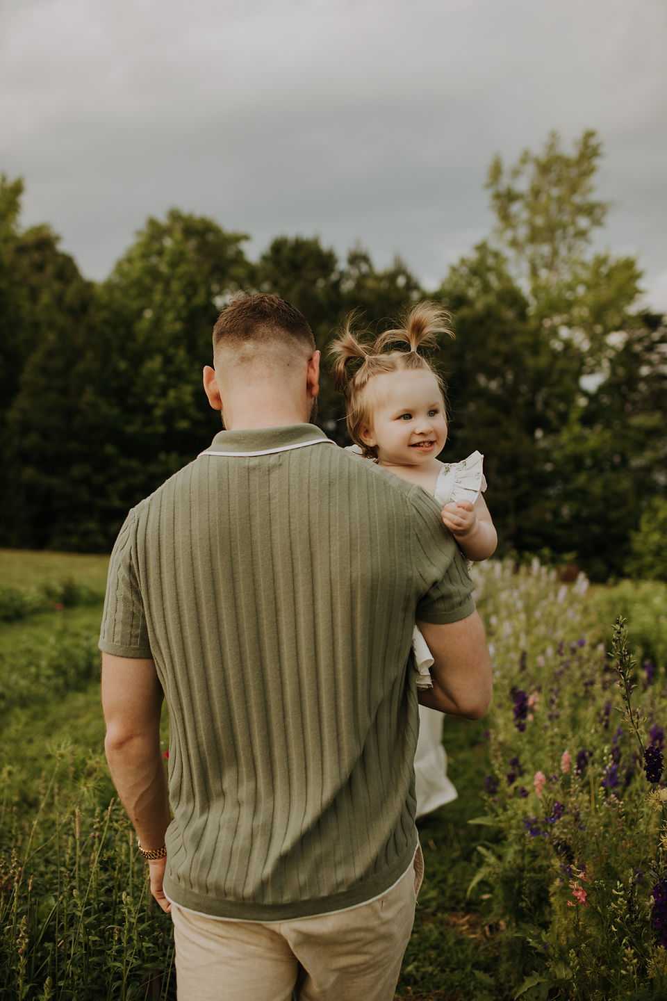 A dad holding his baby girl while she is smiling with pigtails
