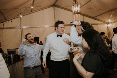 A groom laughing at his friends on the dance floor of his Charlotte wedding reception