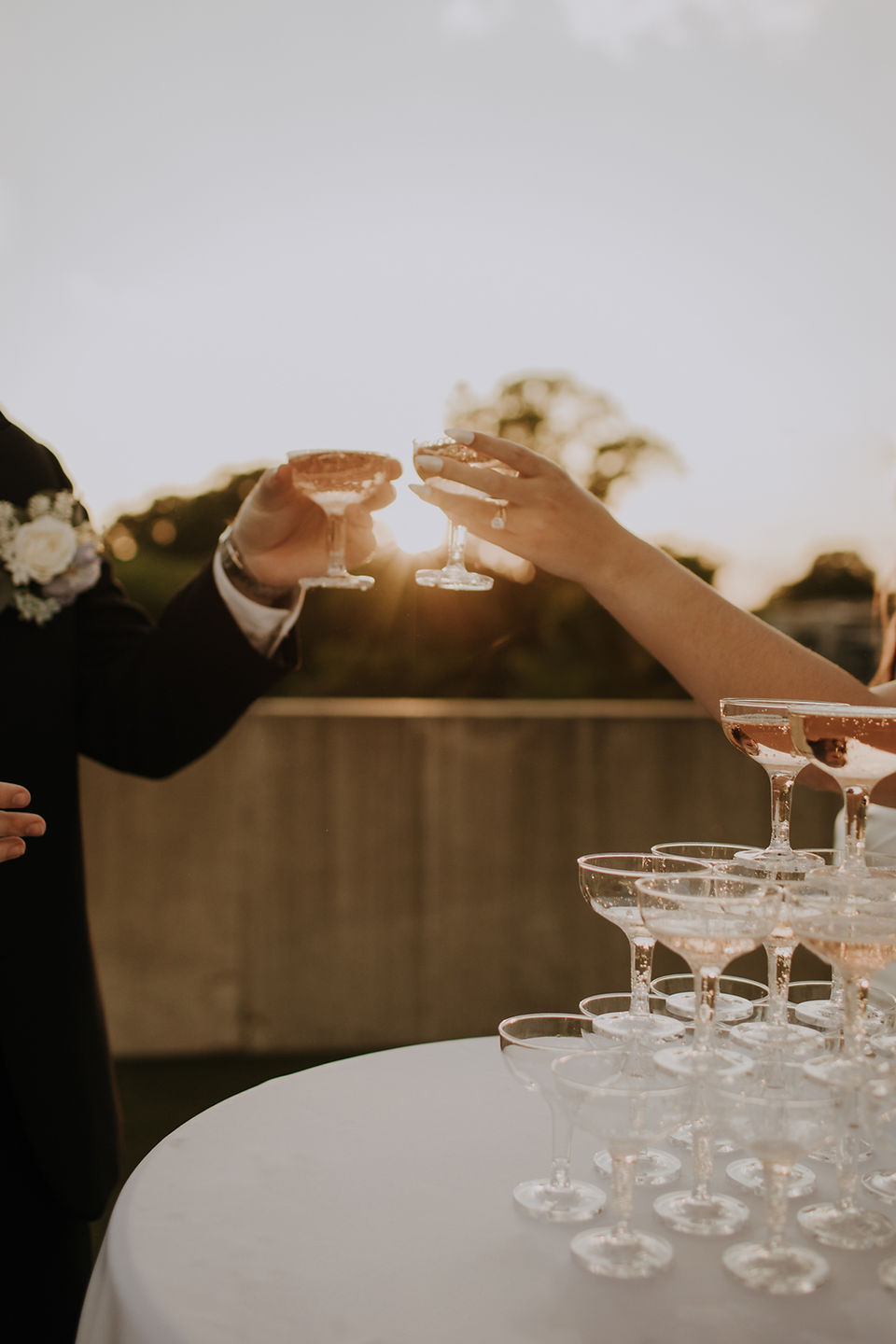 A bride and groom cheers-ing while holding glasses of champagne during golden hour in Charlotte NC