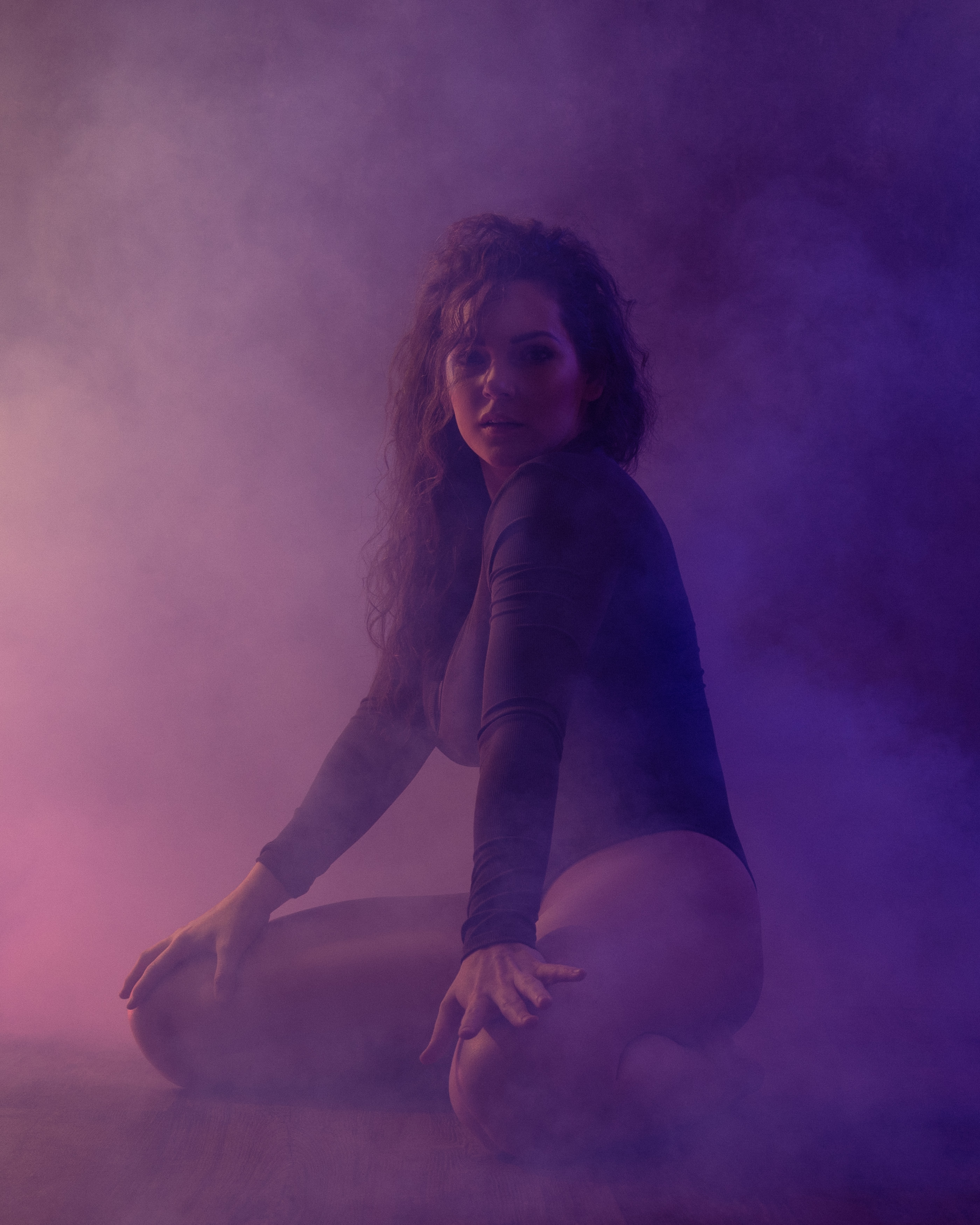 Annie Norris posing in a smoky studio wearing a black bodysuit.