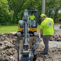 Workers operating excavator during utility installation