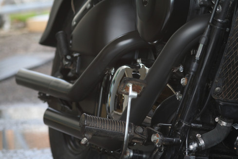 artistic photo of motorcycle footrest and exhaust