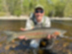 fly angler in a river with a fresh Great Lakes steelhead