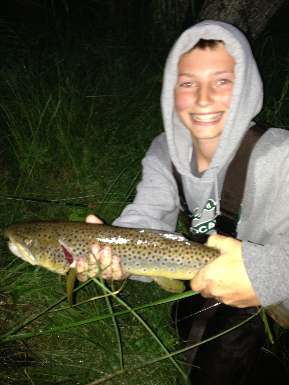 Boy holding a brown trout while fly fishing