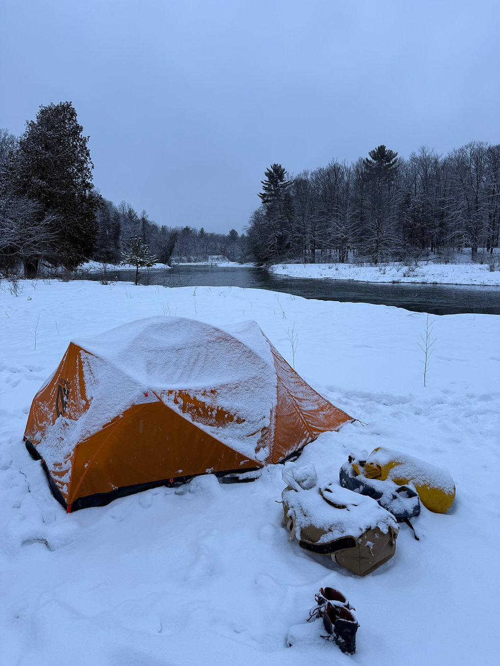 Snow covered tent in a winter scene by a river in Michigan