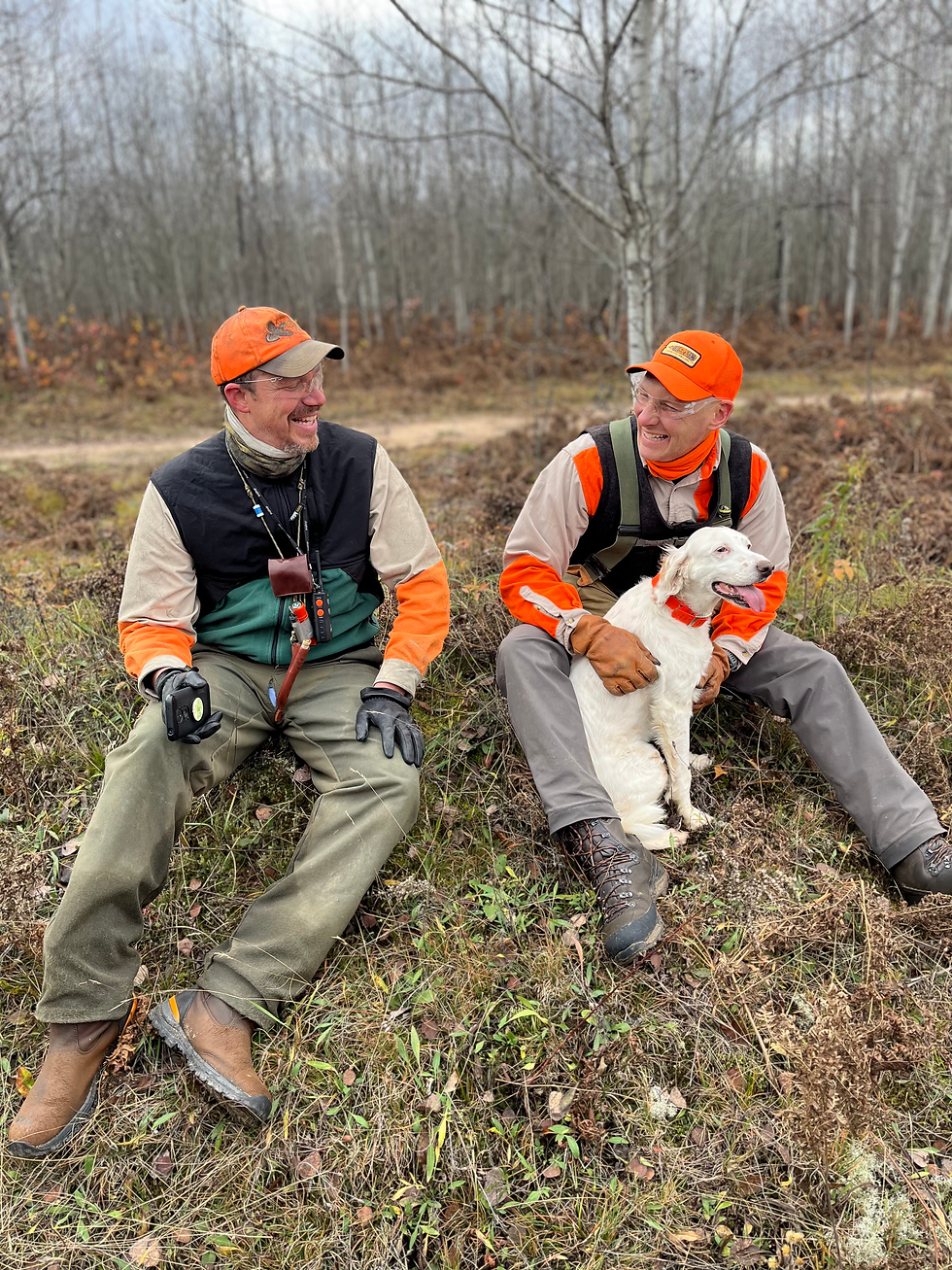 two hunters together laughing, one holds a white bird dog