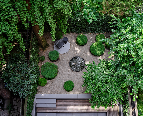 An overhead view of a zen garden with a rounded water feature in the center.
