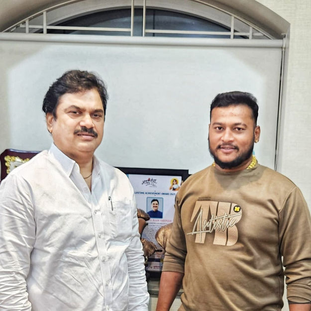 Two men posing for a photo. Visible text: none. Background: office setting.