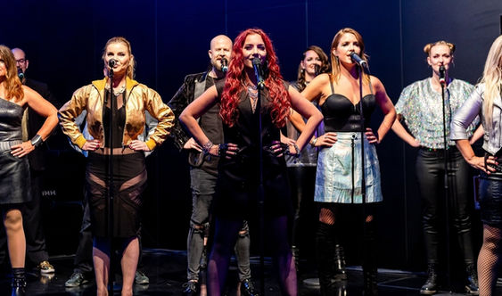 Mehrere Sängerinnen von SPIELHAGEN stehen auf der Bühne und singen bei einer Firmenveranstaltung.