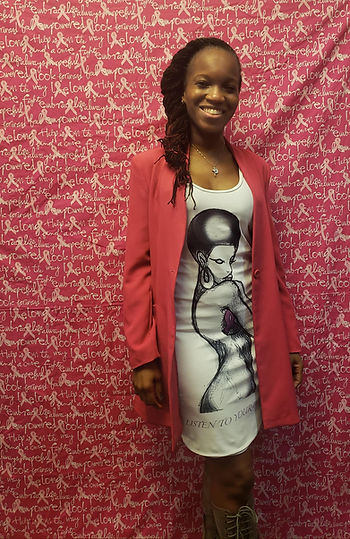 Smiling young woman in pink jacket, patterned dress against pink wall.