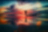Man standing with open arms towards the horizon at sunset.