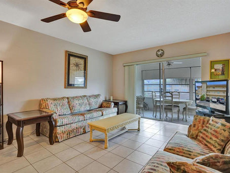 Spacious living room in a Lauderdale Lakes 2-bedroom condo, featuring tile floors, modern furnishings, and enclosed patio access.”