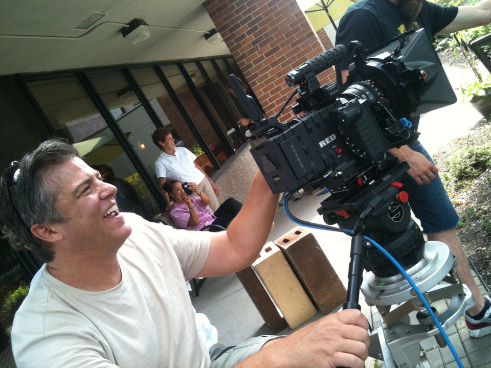 A cinematographer smiling while filming.