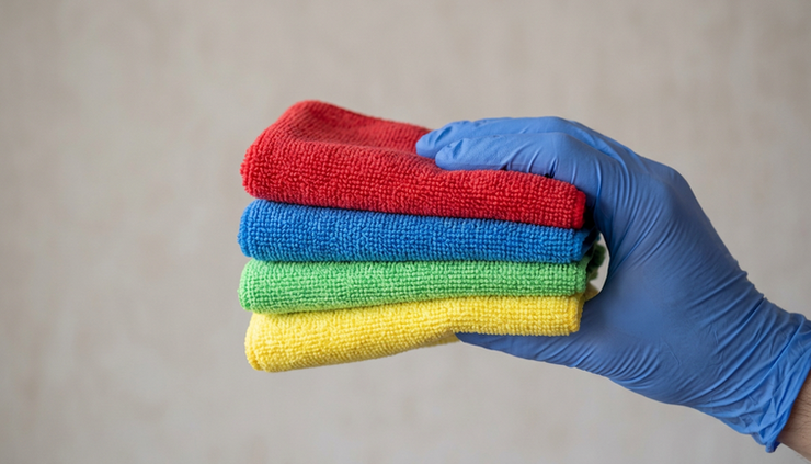 Close-up view of a gloved hand holding colour-coded microfibre cloths