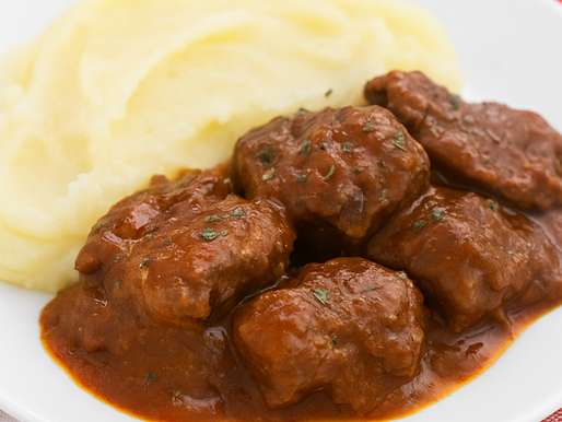Prato de bochechas de porco estufadas com molho e acompanhamento de puré de batata