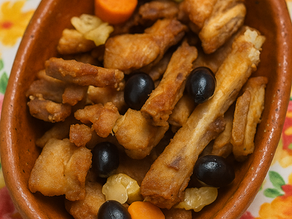 Prato de entrecosto frito dourado, acompanhado de azeitonas e pickles coloridos