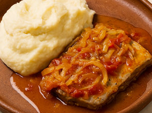 Bifes de atum de cebolada numa frigideira com cebola dourada e molho aromático