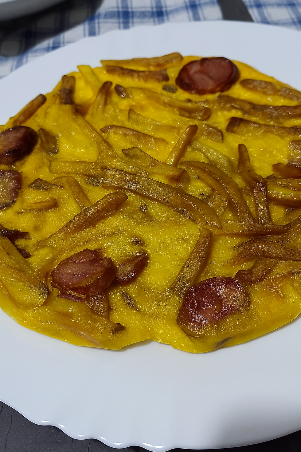 Omelete dourada com batata frita e chouriço num prato de barro português