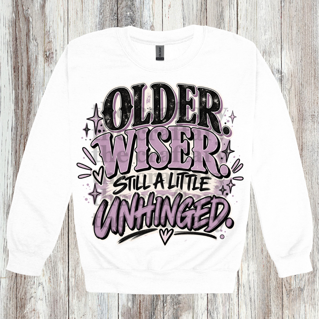 Older Wiser Still A Little Unhinged PNG design shown on a white sweatshirt featuring fun sassy artwork