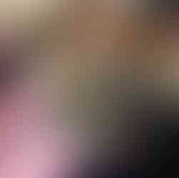 A hand holds a baseball sized felt dryer ball with grey roving felted onto and covering it. The dryer ball is still visible in many places.