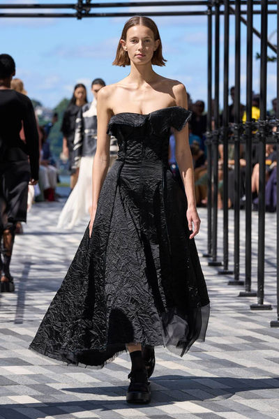 Model in a black strapless dress walking outdoors from Jason Wu's collection, styled with a clean nude manicure by Sofie Roth
