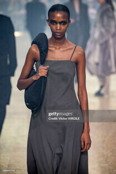 Model on the runway wearing a strapless brown dress from Helmut Lang's collection, showcasing a minimalist nude manicure by Sofie Roth
