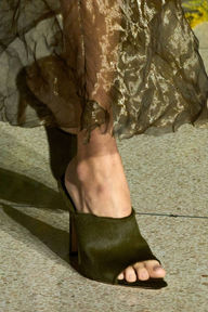 Close-up of a model wearing black heeled sandals with an olive-green dress from Jason Wu's collection, styled with a sophisticated nude manicure by Sofie Roth
