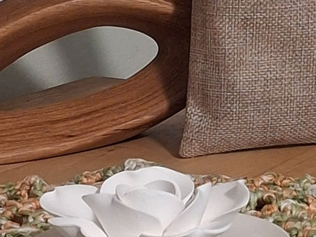 A white ceramic flower aroma stone with a natural linen aromatic sachet and warm wooden sculpture, representing "Rooted," the first signature natural fragrance by aromatherapist Elena Zhidkova-Rice.