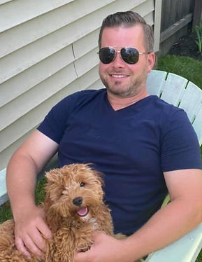 Heritage Roofing Owner Mike Beck holding his dog next to siding
