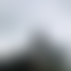 Ein junges Paar steht vor einem weißen Leuchtturm hinter Palmen.