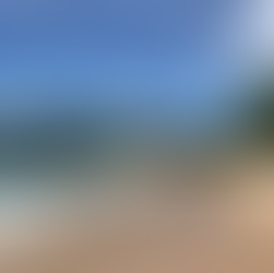 Ein menschenleerer Strand und türkis, blauem Meer mit weißer Gischt.