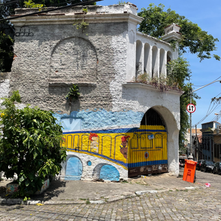Ein graues Gebäude mit Streetart, welche eine gelbe Bahn auf einer Brücke zeigt.