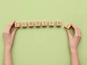 A pair of hands use wood blocks to spell out cortisol
