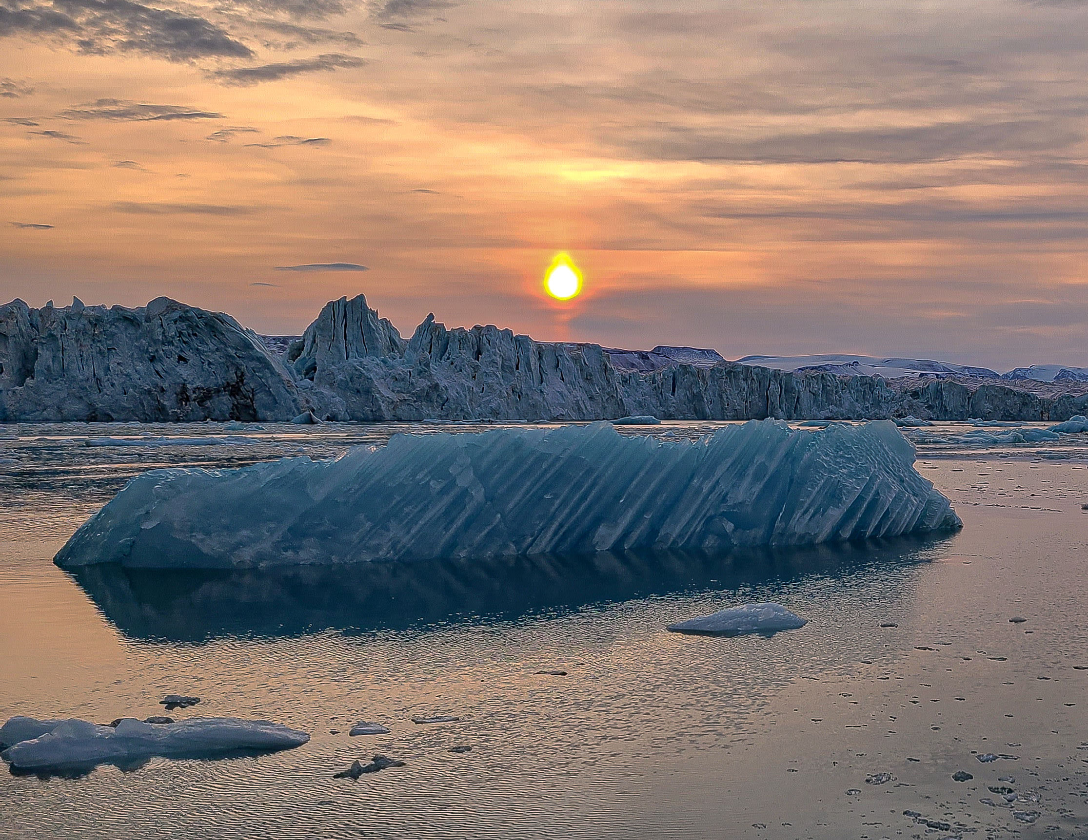 White-Striped Iceberg and Glacier Beneath Blazing Sunset