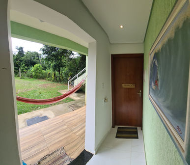 corredor de entrada de suíte com uma cama de casal, uma de solteiro e uma cama retrátil em uma pousada localizada em Ubatuba/SP - Brasil
