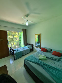 suíte com uma cama de casal e uma de solteiro em uma pousada localizada em Ubatuba/SP - Brasil