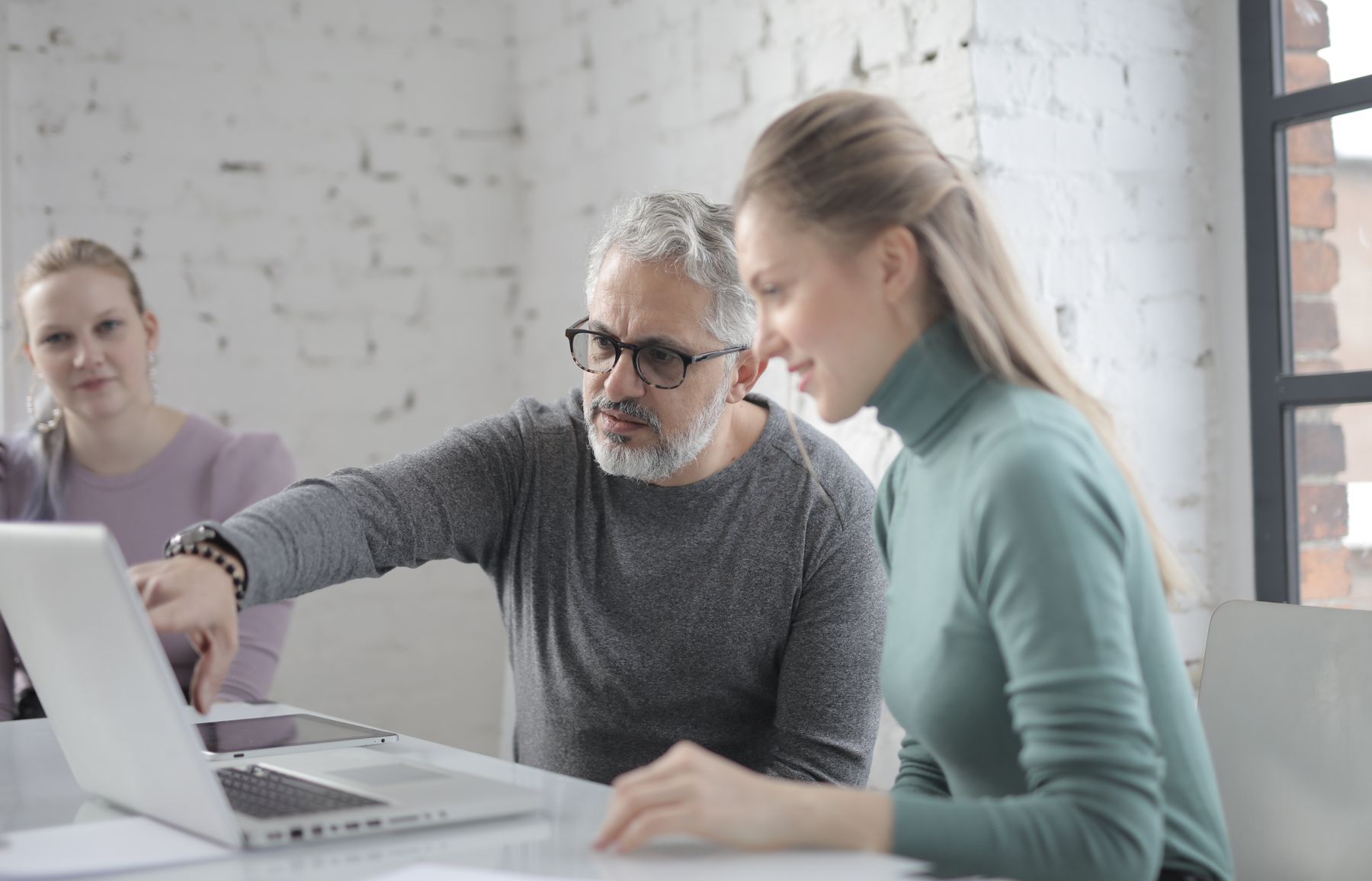 Senior en junior collega werken samen achter een laptop